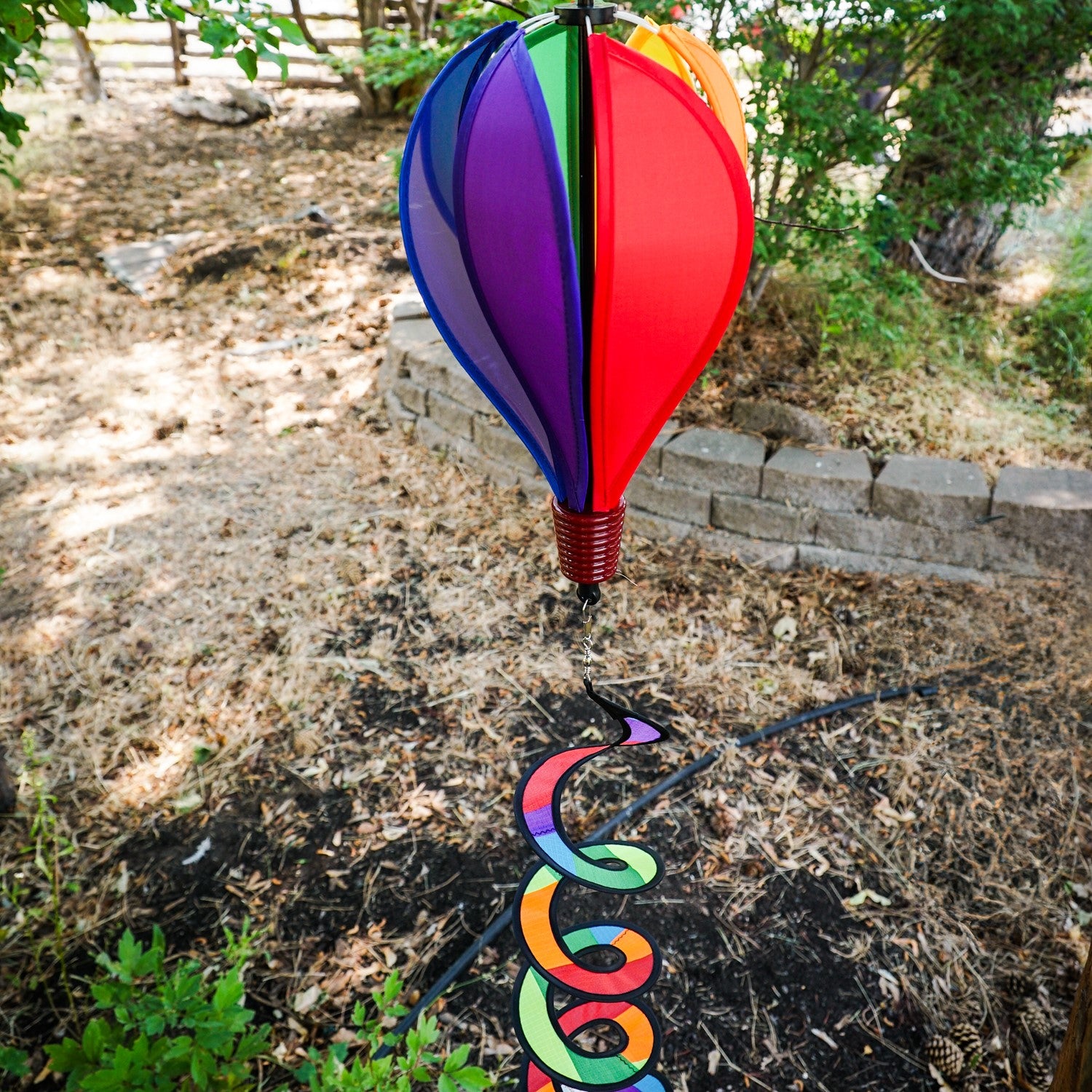 Mini Rainbow Hot Air Balloon spinner featuring colorful panels in a garden setting, designed to spin and delight in light breezes.