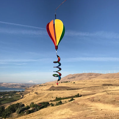 Mini Rainbow Hot Air Balloon spinner featuring colorful panels in a garden setting, designed to spin and delight in light breezes.
