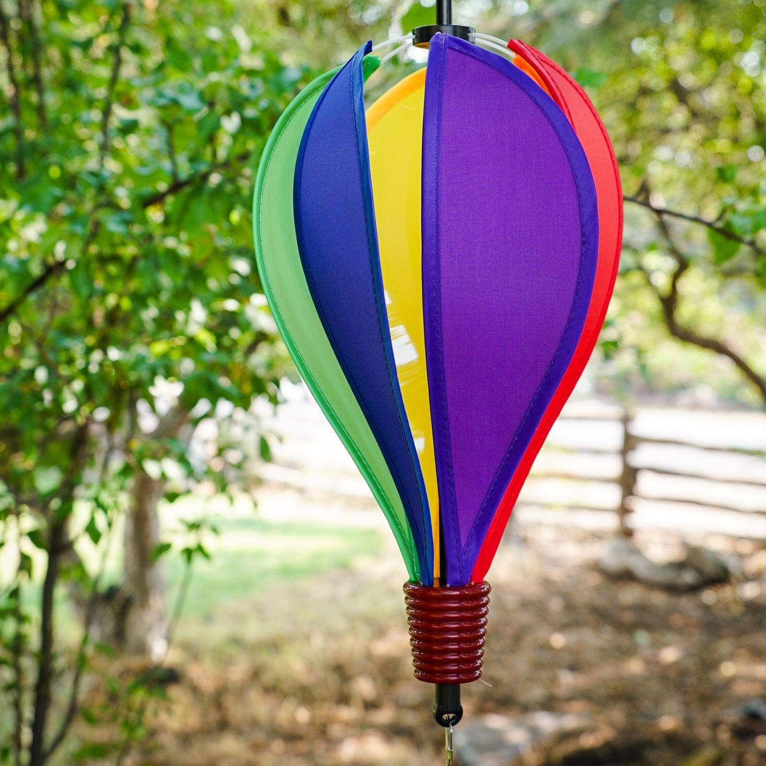 Mini Rainbow Hot Air Balloon spinner featuring colorful panels in a garden setting, designed to spin and delight in light breezes.