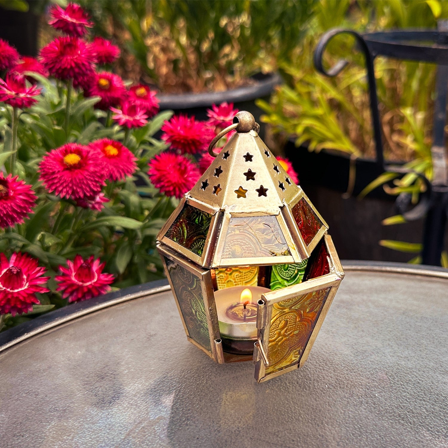 Mini Red, Yellow & Green Hex Glass Tealight Lantern showcasing vibrant colors with intricate metal accents, designed for tealights, hanging in an outdoor setting.