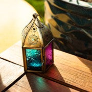 Mini Teal & Pink Pentagon Glass Tealight Lantern showcasing a vibrant design with textured glass panels and metal accents in a cozy indoor setting.
