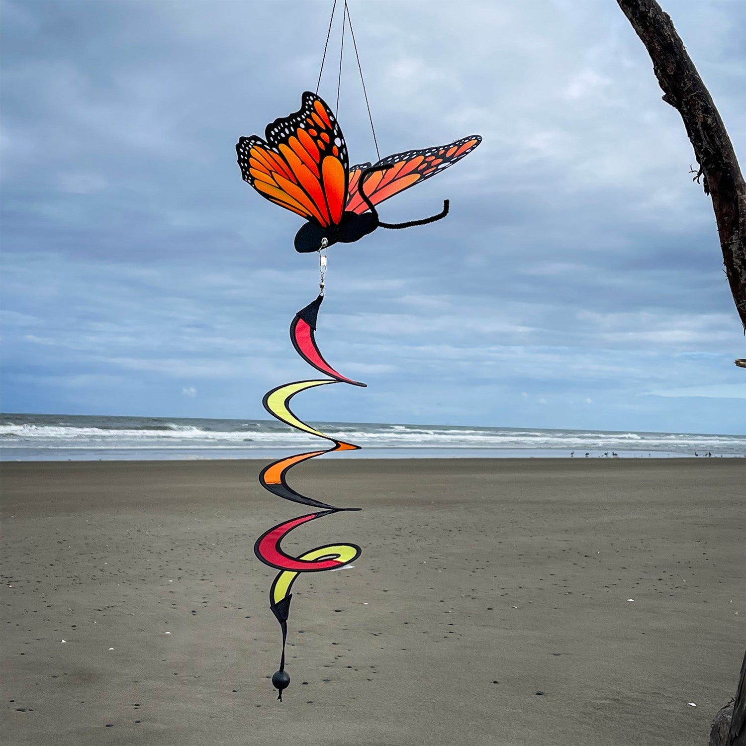 Monarch Butterfly Theme Twister featuring moveable wings and a curlie tail, hanging gracefully in a vibrant outdoor garden setting.