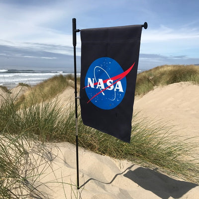 NASA Lustre Garden Flag with double-sided logo design against a black background displayed in a garden setting.