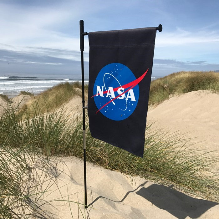 NASA Lustre Garden Flag with double-sided logo design against a black background displayed in a garden setting.