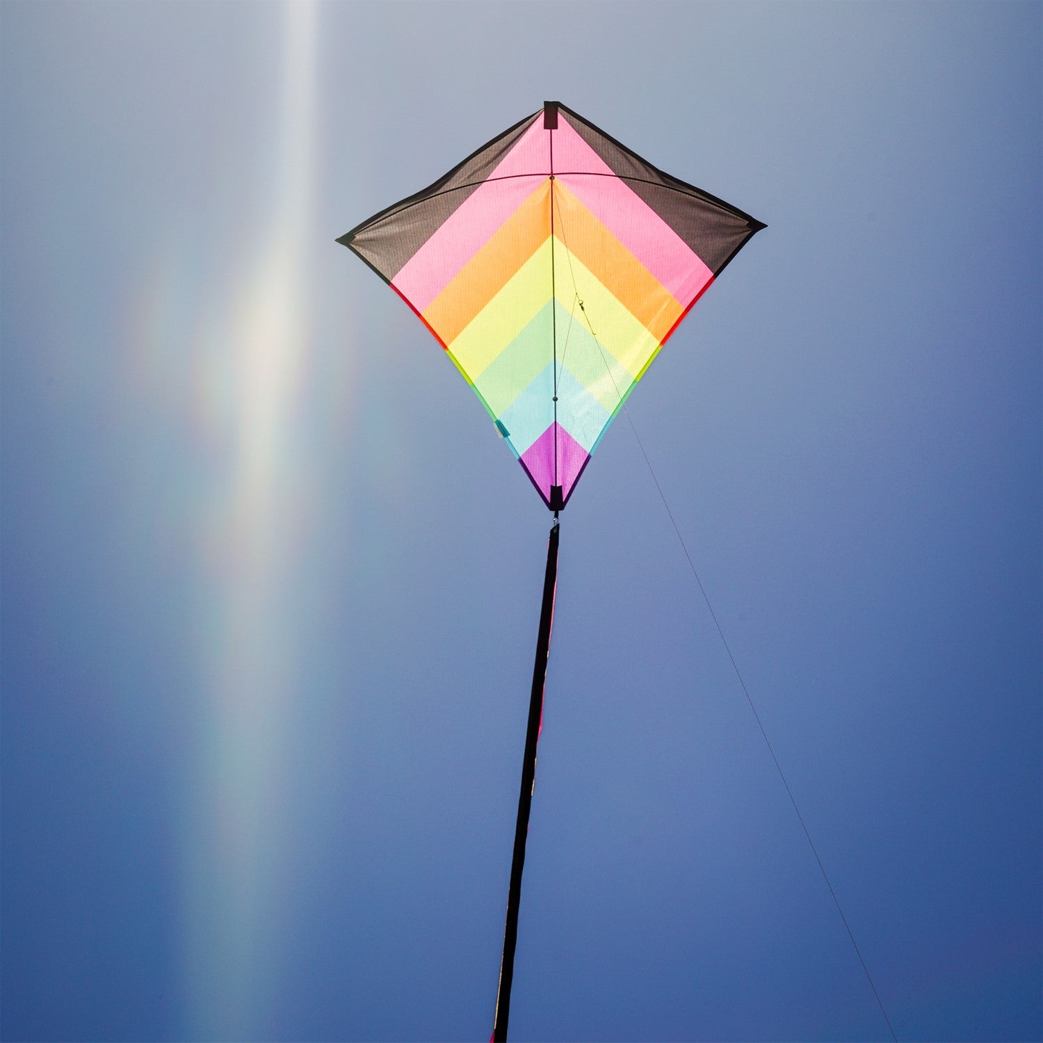 Neon Fiesta 30' Diamond Kite flying in a clear blue sky, featuring bright colors and long flowing tails, showcasing its stunning design.