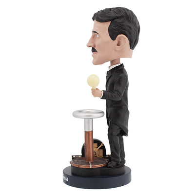 Nikola Tesla Bobblehead figurine capturing Tesla's likeness, detailed with hand-painted features, displayed on a desk among books.