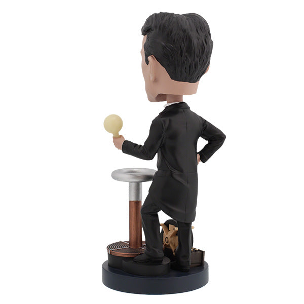 Nikola Tesla Bobblehead figurine capturing Tesla's likeness, detailed with hand-painted features, displayed on a desk among books.