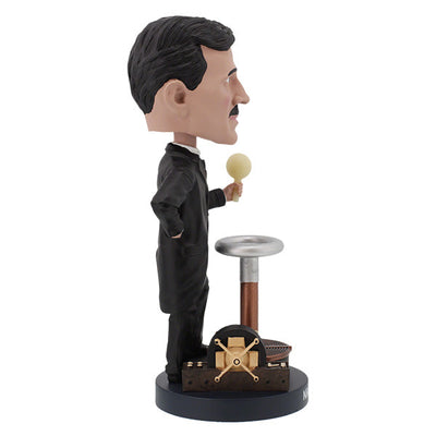 Nikola Tesla Bobblehead figurine capturing Tesla's likeness, detailed with hand-painted features, displayed on a desk among books.