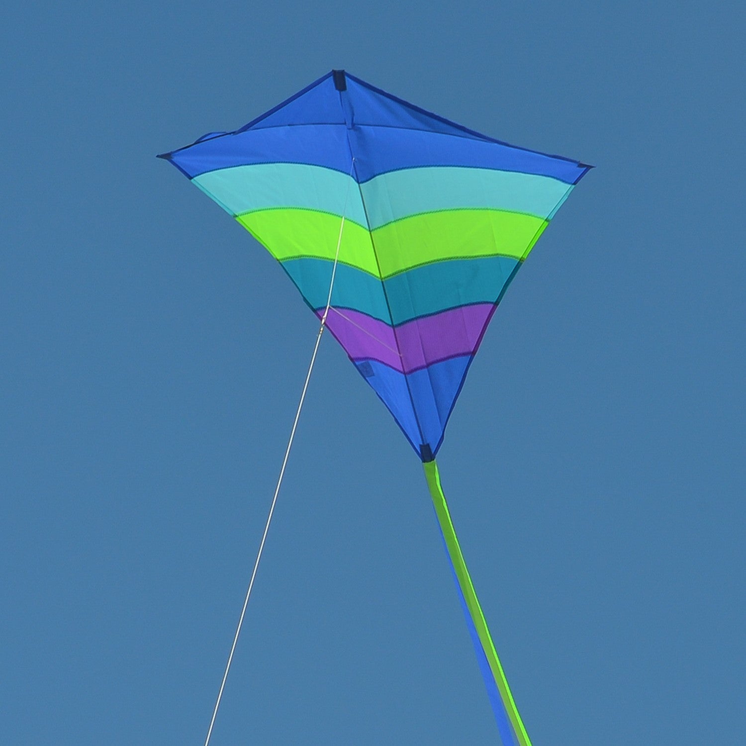 The Ocean Arch 39" Diamond Kite features a stunning blue and ocean-themed design, showcasing its durable ripstop fabric and long tails as it soars high in clear skies.
