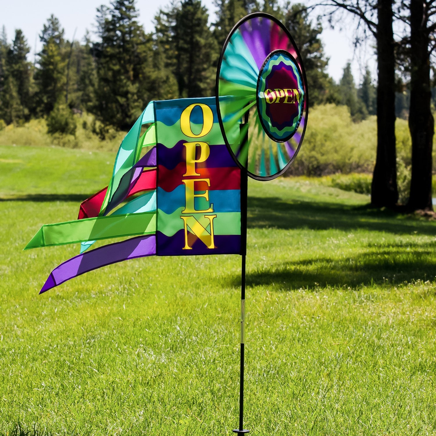 Open Spinner Wheel with Garden Flag & Tails displaying 'Open for Business' in vivid colors, rotating in a gentle breeze at an outdoor location.