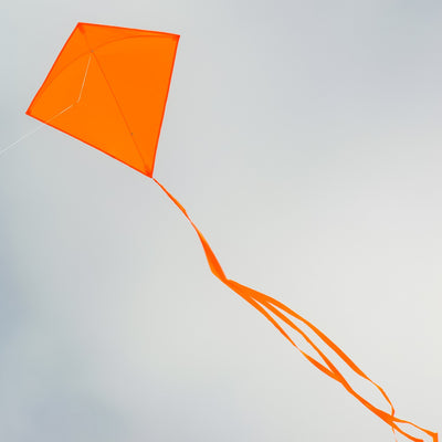 Orange Colorfly 30" Diamond Kite with vivid orange color and three 12' tails displayed in the sky during a sunny day, signifying outdoor fun.
