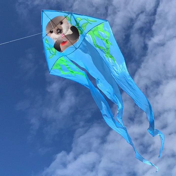 Otter 52' Wave Delta Kite with playful otter design soaring against a bright blue sky, showcasing its vibrant colors and flowing tails.