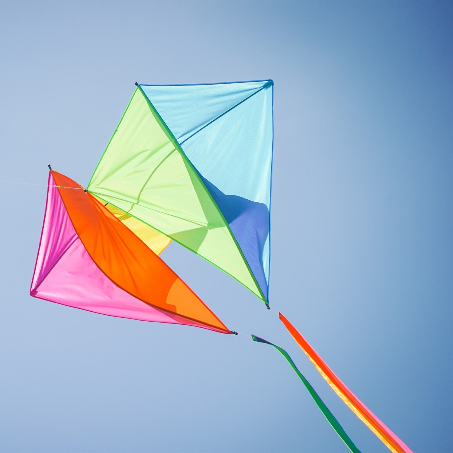 Pacific Dancing Diamonds Kite with colorful diamond panel design soaring in the sky, featuring attached tails and displayed at a kite flying event.