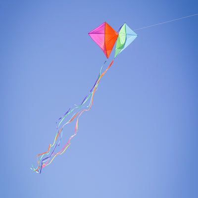 Pacific Dancing Diamonds Kite with colorful diamond panel design soaring in the sky, featuring attached tails and displayed at a kite flying event.