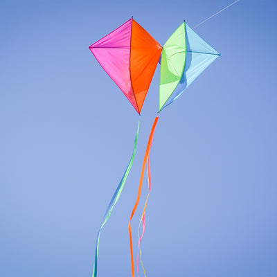 Pacific Dancing Diamonds Kite with colorful diamond panel design soaring in the sky, featuring attached tails and displayed at a kite flying event.