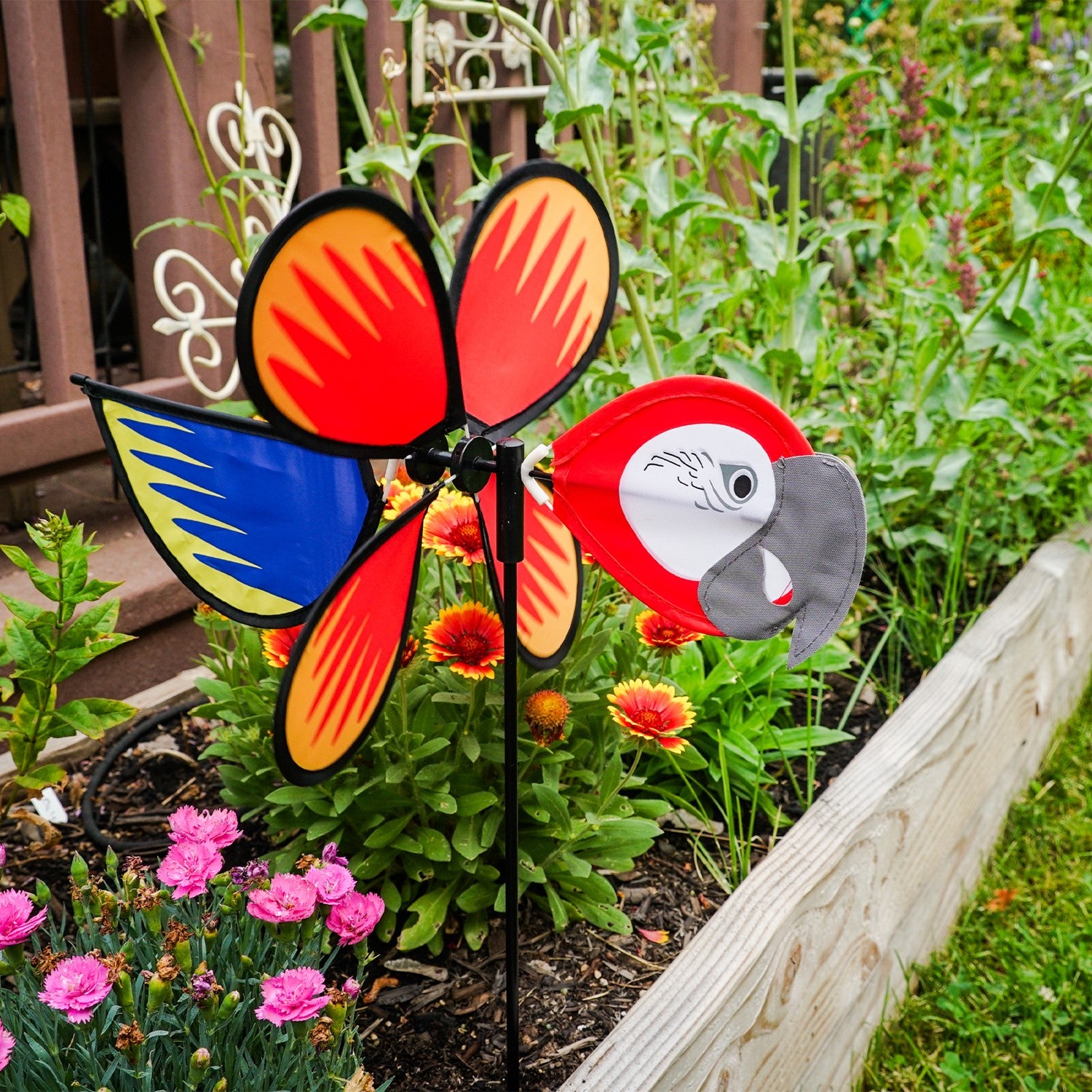 Parrot Baby Spinner featuring bright colors and detailed graphics, spinning easily on a 17-inch fiberglass pole in a garden setting.