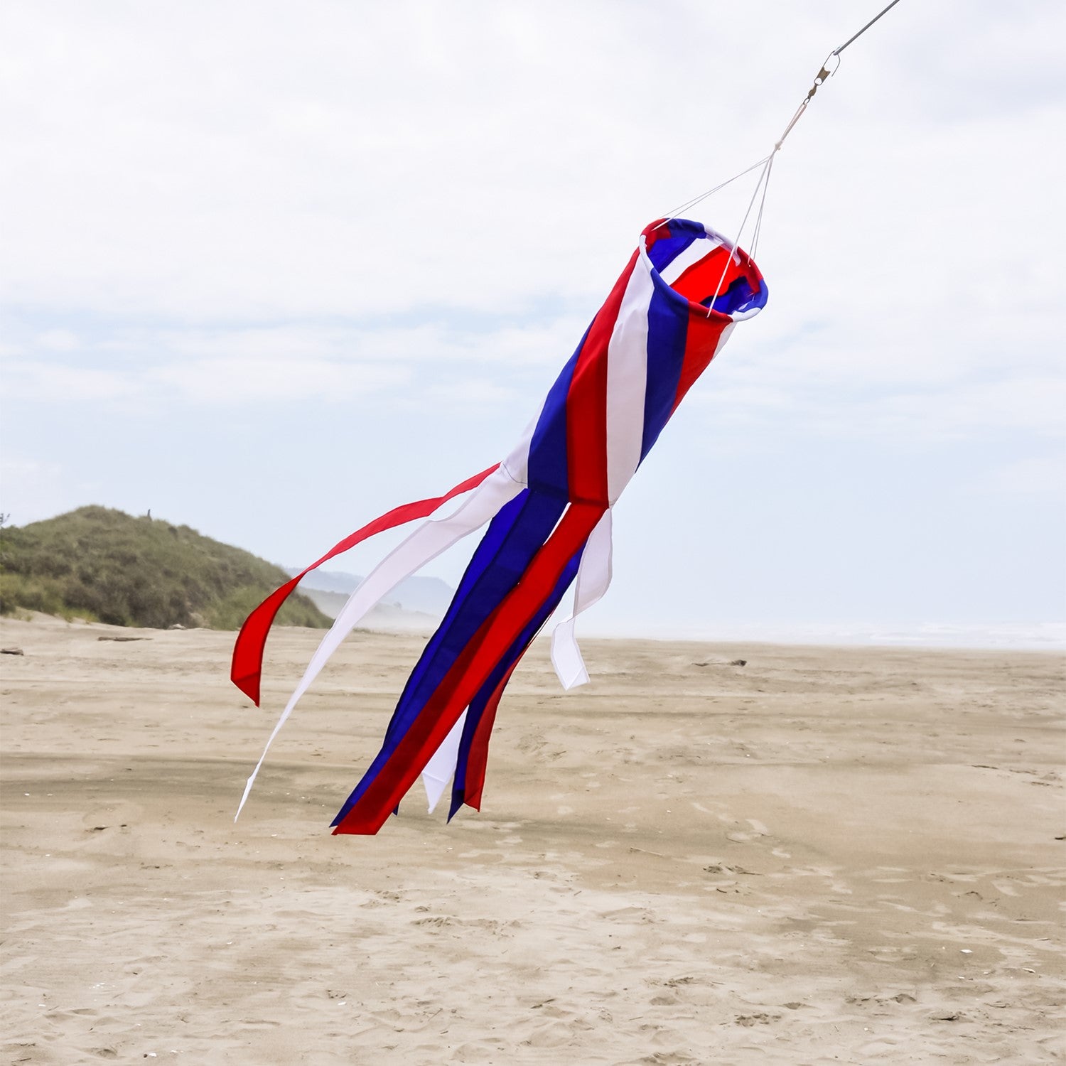 Patriot Diagonal 40'' Windsock featuring red, white, and blue colors with fluttering tails, displayed outdoors, embodying patriotic spirit.