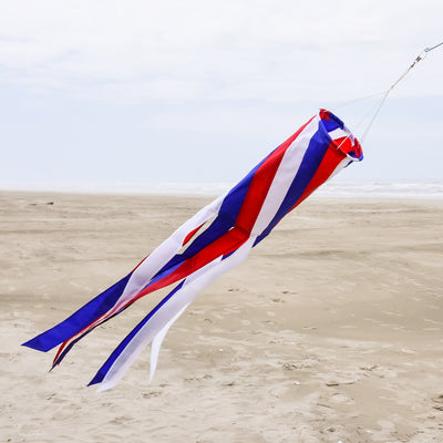 Patriot Diagonal 40'' Windsock featuring red, white, and blue colors with fluttering tails, displayed outdoors, embodying patriotic spirit.