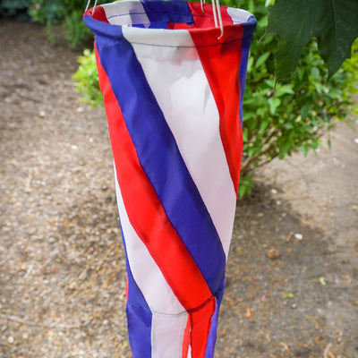 Patriot Diagonal 40'' Windsock featuring red, white, and blue colors with fluttering tails, displayed outdoors, embodying patriotic spirit.