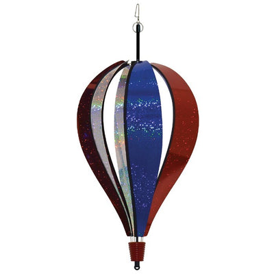 Patriot Sparkler 6-Panel Hot Air Balloon spinning in a garden, showcasing its vibrant red, white, and blue Mylar design against a blue sky.