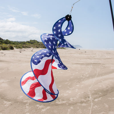 Patriot Spin Duet double spinner decoration featuring red, white, and blue stars and stripes design hanging outdoors in a garden setting.