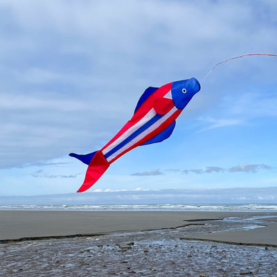 Patriot Trout 48" Fishsock in vibrant red, white, and blue swaying in the breeze from a hanging point in a garden setting.