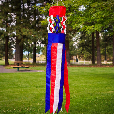 Patriot Twistair windsock featuring red, white, and blue colors with twisted curls, elegantly displayed in a garden setting.