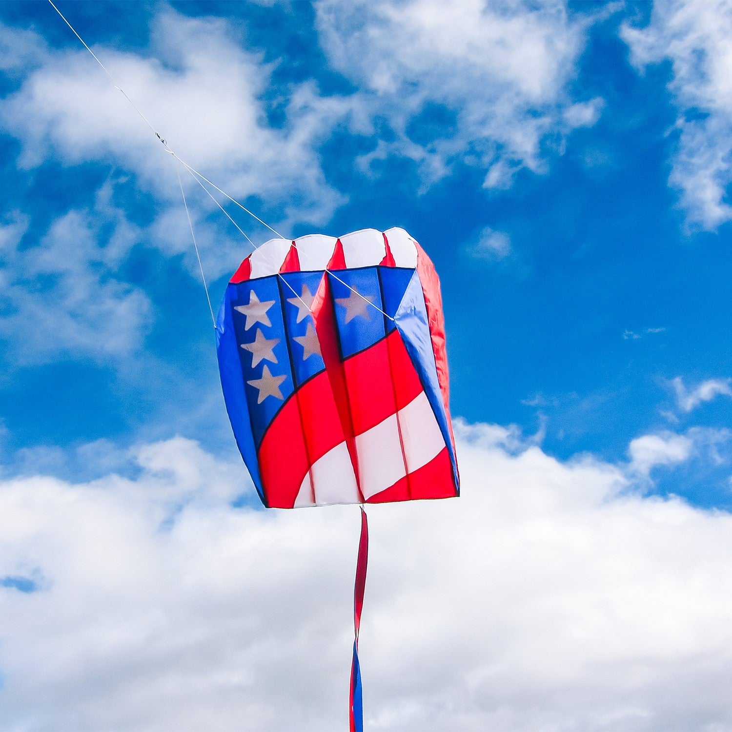 7.5 Patriot Wave Air Foil Kite soaring in the sky with red, white, and blue colors and stars, showcasing its lightweight design and beauty.