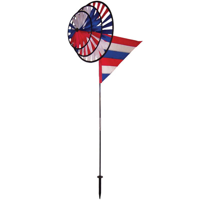 Patriot Wind Sail Triple Wheel Spinner with three colorful wheels and an applique windsail, displayed in an outdoor garden setting, showcasing red, white, and blue colors.