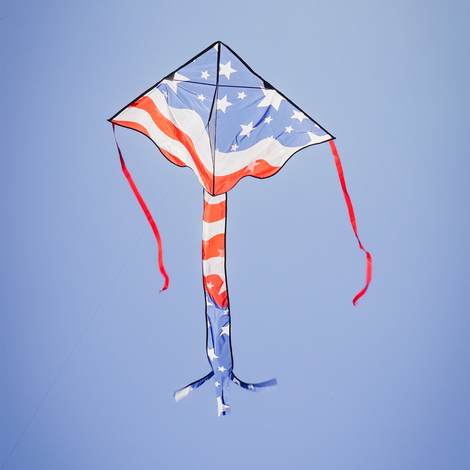 Patriotic 46" Fly-Hi Kite soaring in the sky with vibrant stars and stripes design, flying in a clear blue background during a sunny day.