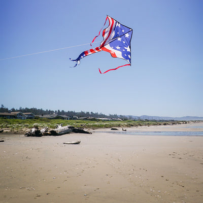 Patriotic 46" Fly-Hi Kite soaring in the sky with vibrant stars and stripes design, flying in a clear blue background during a sunny day.