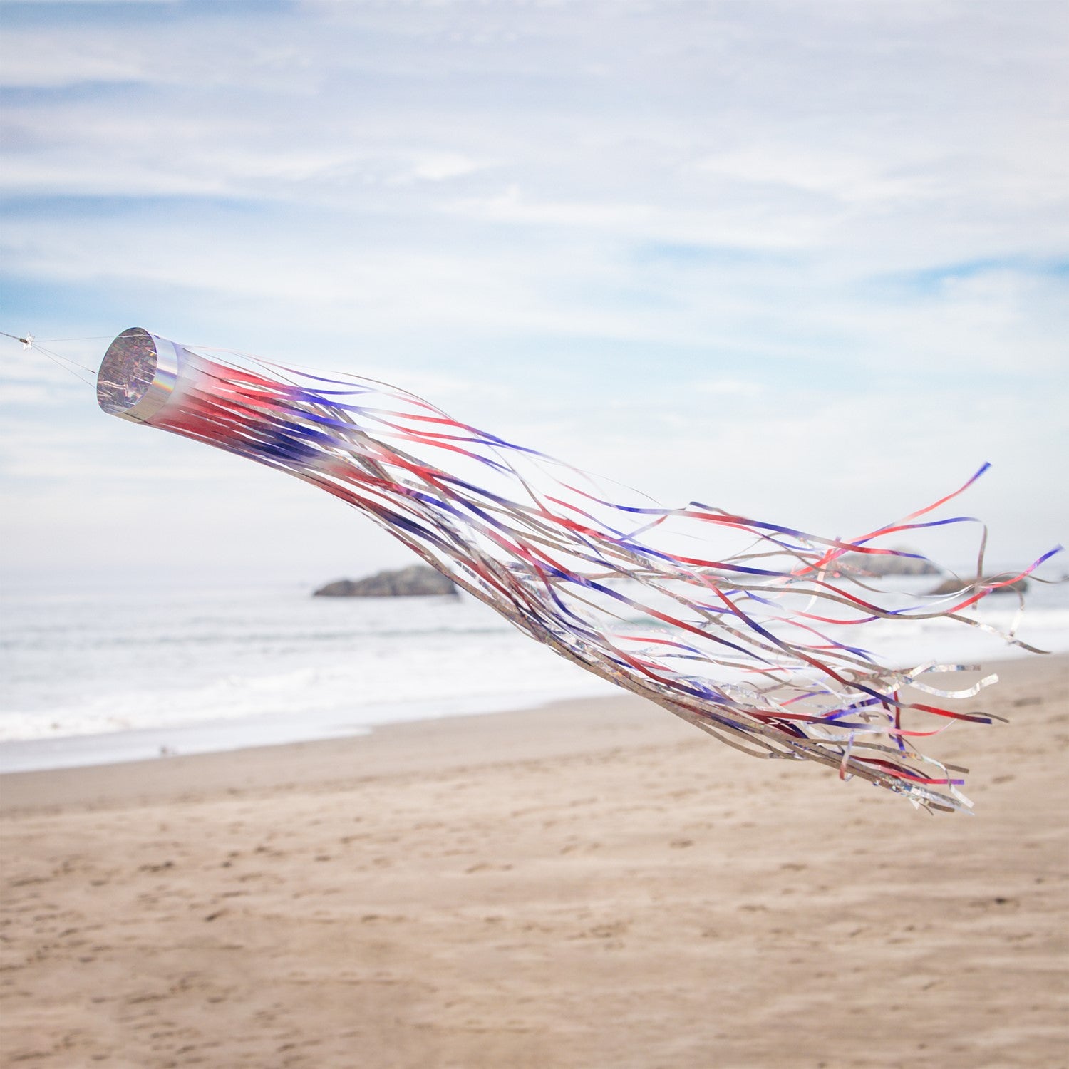 Patriotic 51 inch Mylar windsock in red, white, and blue, shimmering in sunlight while fluttering in the breeze, perfect for festive outdoor decoration.