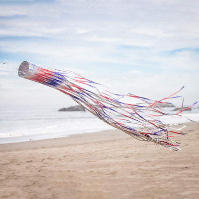 Patriotic 51 inch Mylar windsock in red, white, and blue, shimmering in sunlight while fluttering in the breeze, perfect for festive outdoor decoration.