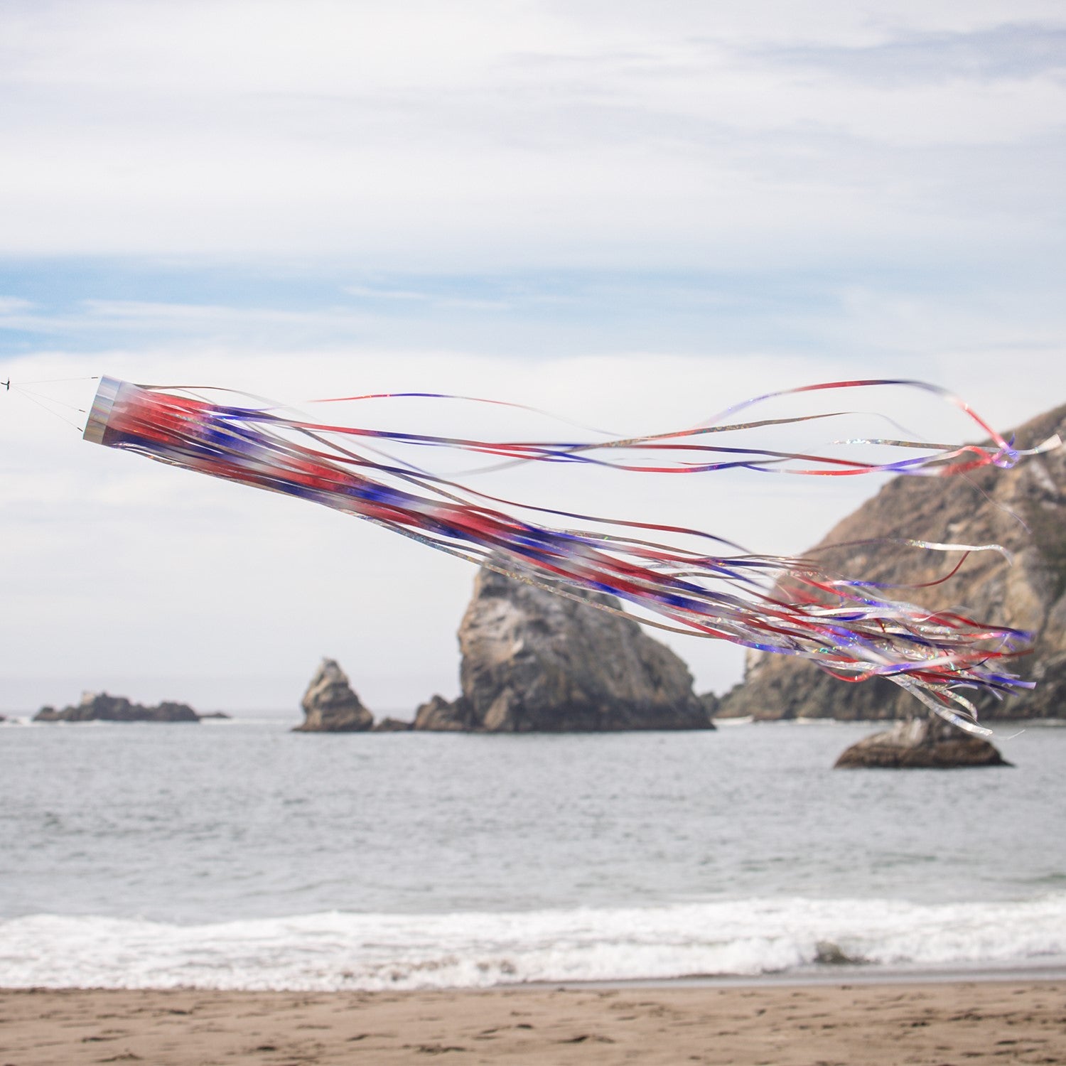 Patriotic 51 inch Mylar windsock in red, white, and blue, shimmering in sunlight while fluttering in the breeze, perfect for festive outdoor decoration.