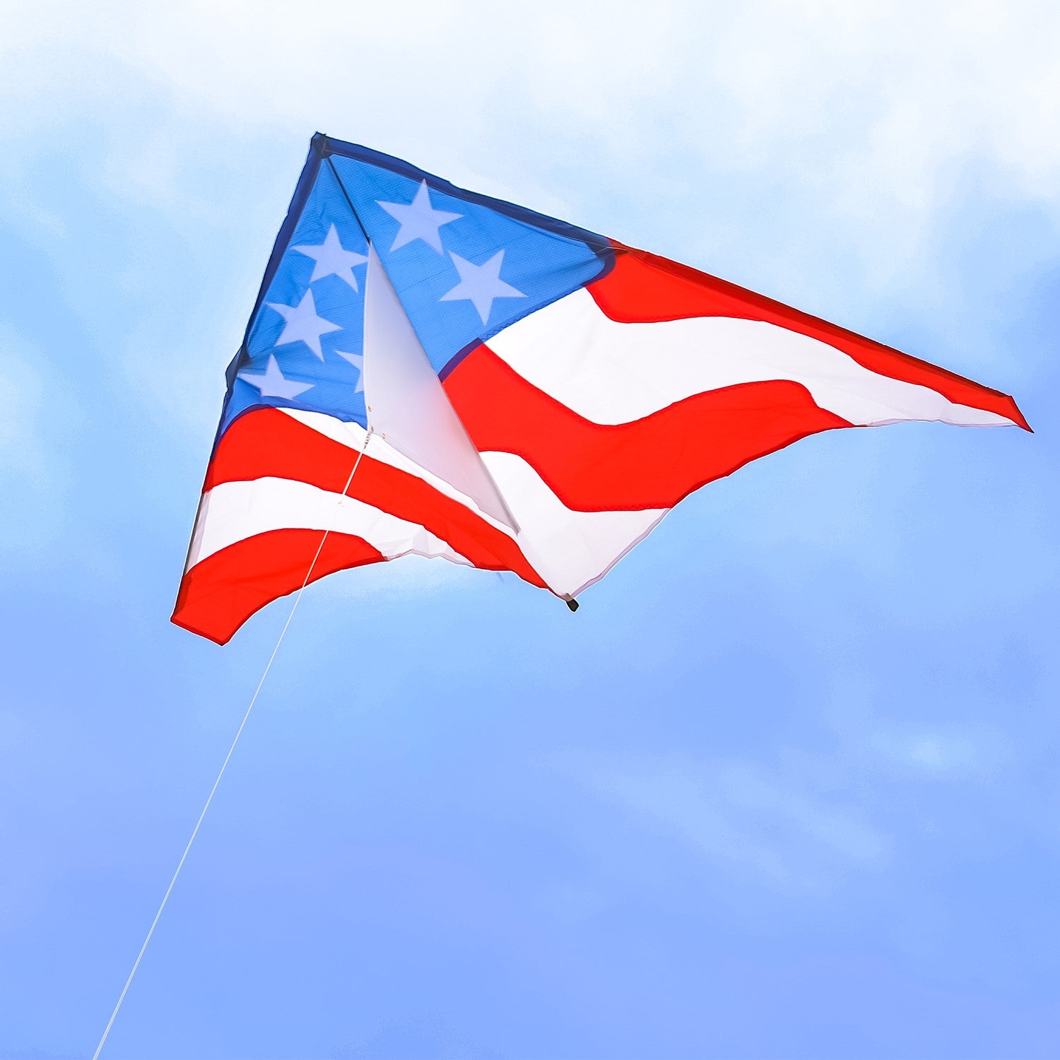 Patriotic 57 inch Delta Kite with red, white, and blue stars and stripes design soaring high in the blue sky against a sunny backdrop.