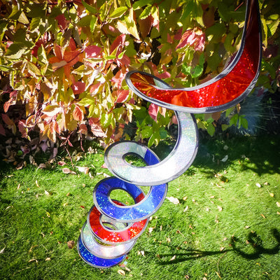 Patriotic Sparkle Curlie in red, white, and blue waving in the breeze, showcasing its 48-inch dazzling Mylar design with tails.