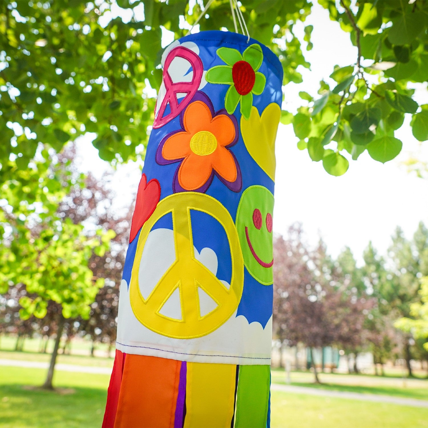 Peace, Love & Happiness 40-inch windsock with psychedelic designs and colorful tails, fluttering in the breeze outdoors.