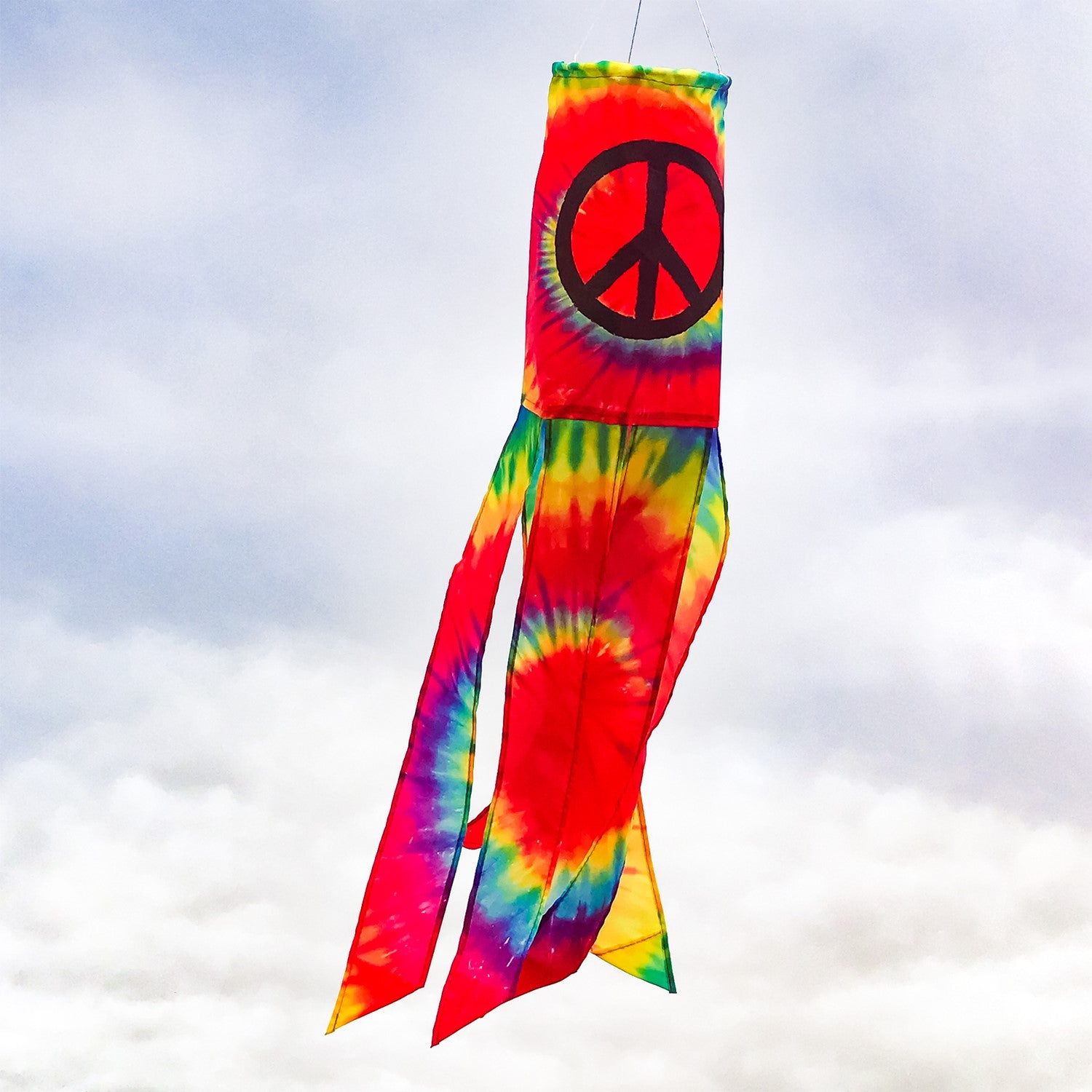 Vibrant Peace Sign 30" windsock displaying colorful tie-dye design with six tails, fluttering in the breeze in an outdoor setting.