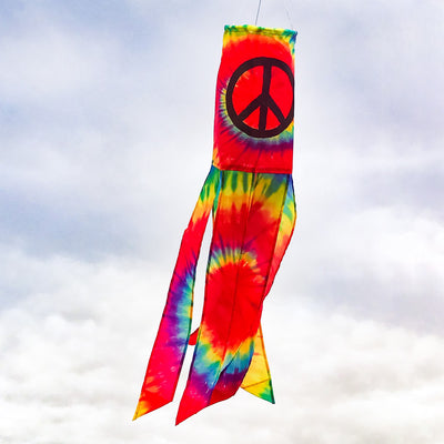 Vibrant Peace Sign 30" windsock displaying colorful tie-dye design with six tails, fluttering in the breeze in an outdoor setting.
