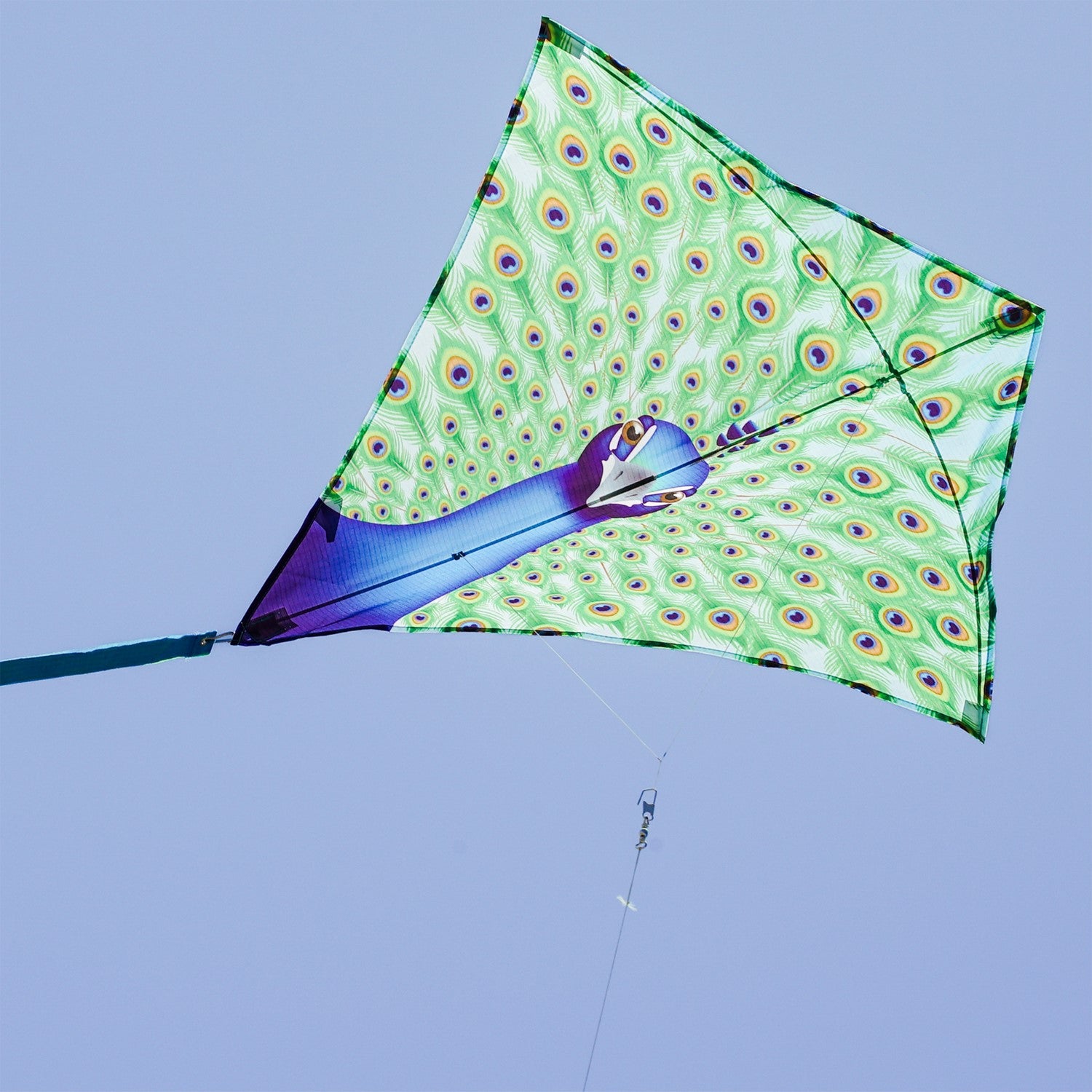 Colorful Peacock 30-inch Diamond Kite flying in the blue sky with vibrant feather design and tails trailing behind, perfect for kids and families.