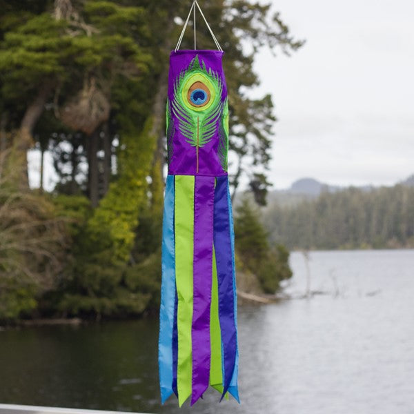 Peacock Feather 40" Windsock shown outdoors, fluttering in the breeze, adding vibrant color and motion to any garden or outdoor space, ideal for decor enthusiasts.