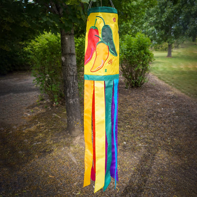 A colorful Pepper Fiesta 40" windsock featuring cheerful chili peppers and fluttering tails hanging gracefully in an outdoor garden setting.