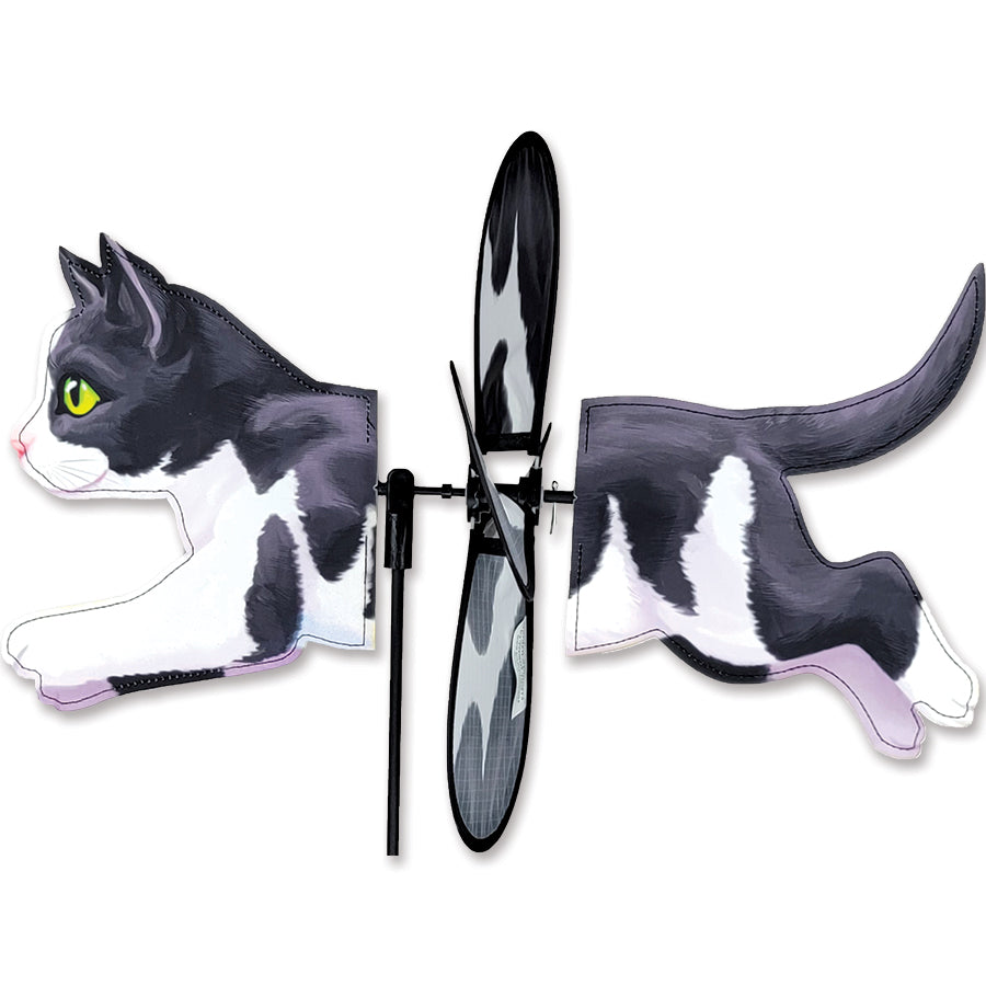 Petite Spinner featuring a playful black and white cat design, spinning in the wind among garden flowers, showcasing its charming appeal.