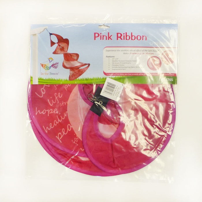 A Pink Ribbon Spin Duet hanging in a garden, featuring vibrant pink ribbon graphics and a spinning mechanism, symbolizing breast cancer awareness.