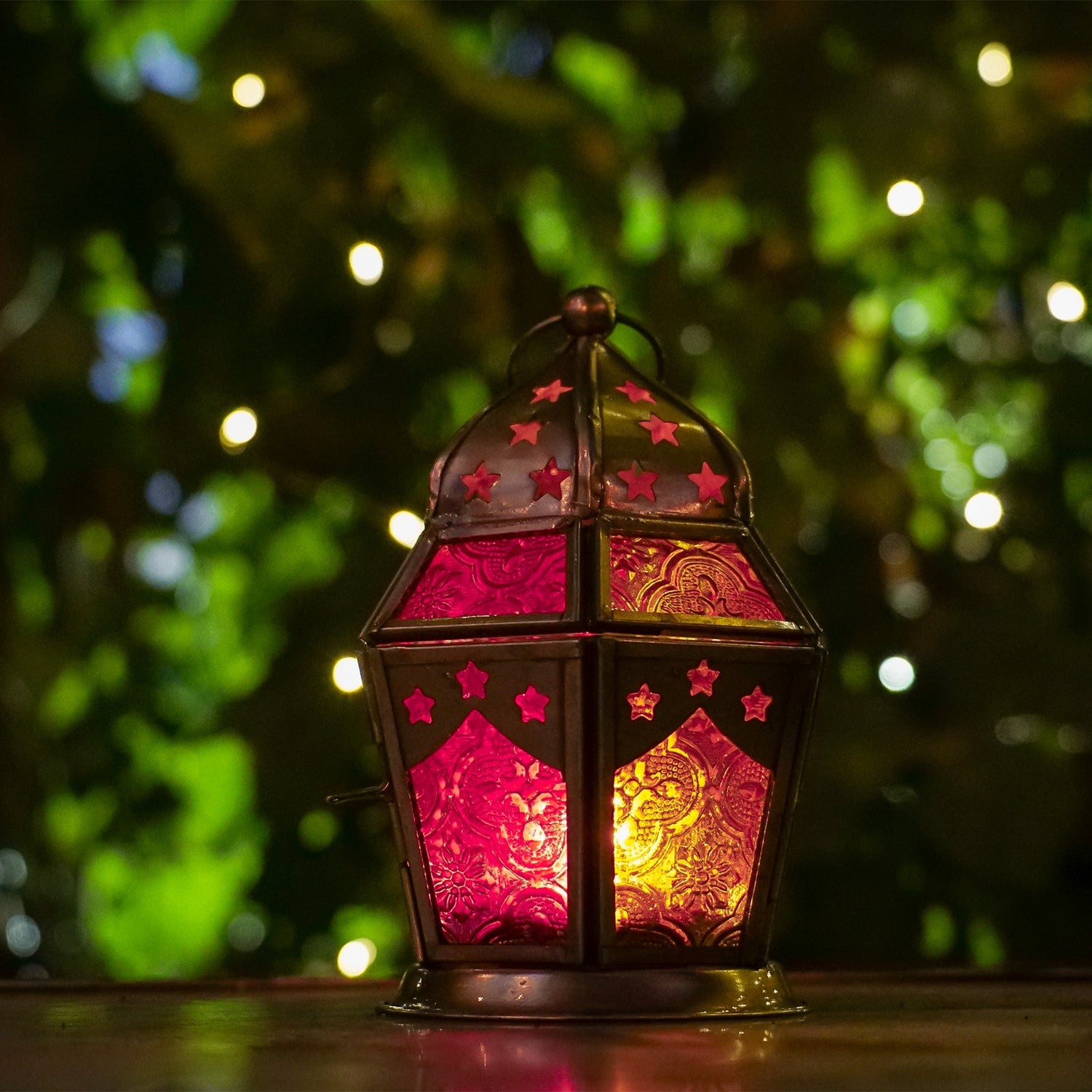 Pink and yellow hex glass tealight lantern with stamped designs and metal frame, elegantly displaying a tealight candle in a cozy setup.