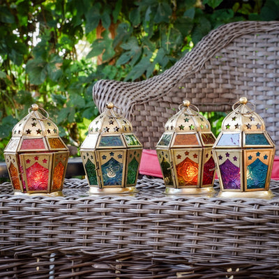 Pink and yellow hex glass tealight lantern with stamped designs and metal frame, elegantly displaying a tealight candle in a cozy setup.