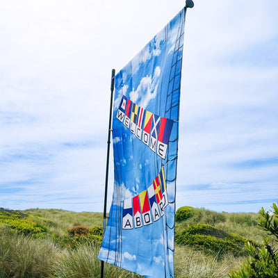 Pivoting House Banner Pole displaying a 28x40 house banner, showcasing its durable fiberglass and metal design in an outdoor garden setting.