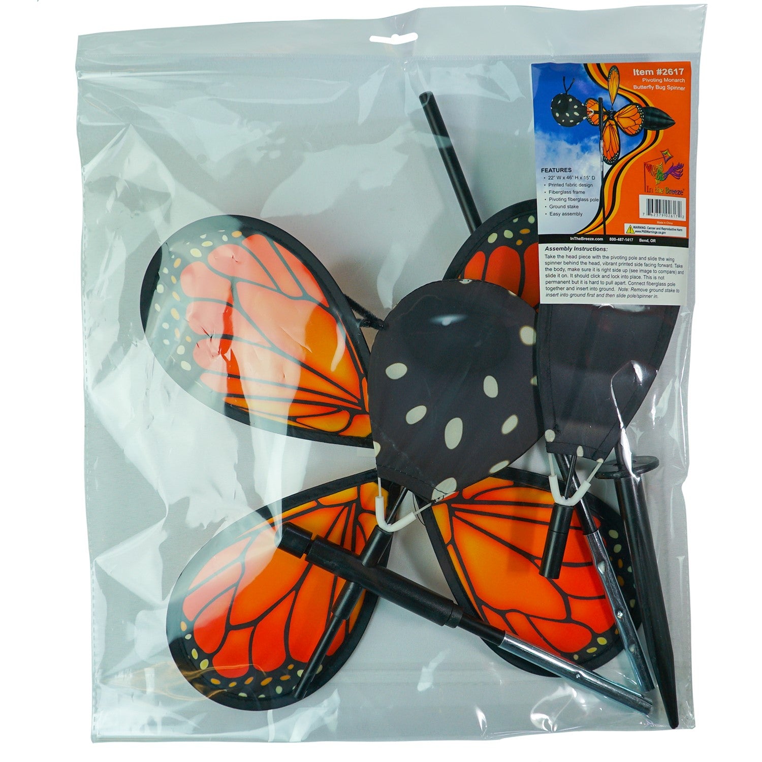 Vibrant Pivoting Monarch Butterfly Spinner in a garden, showcasing colorful petal design and fiberglass frame, adding motion to the outdoor space.