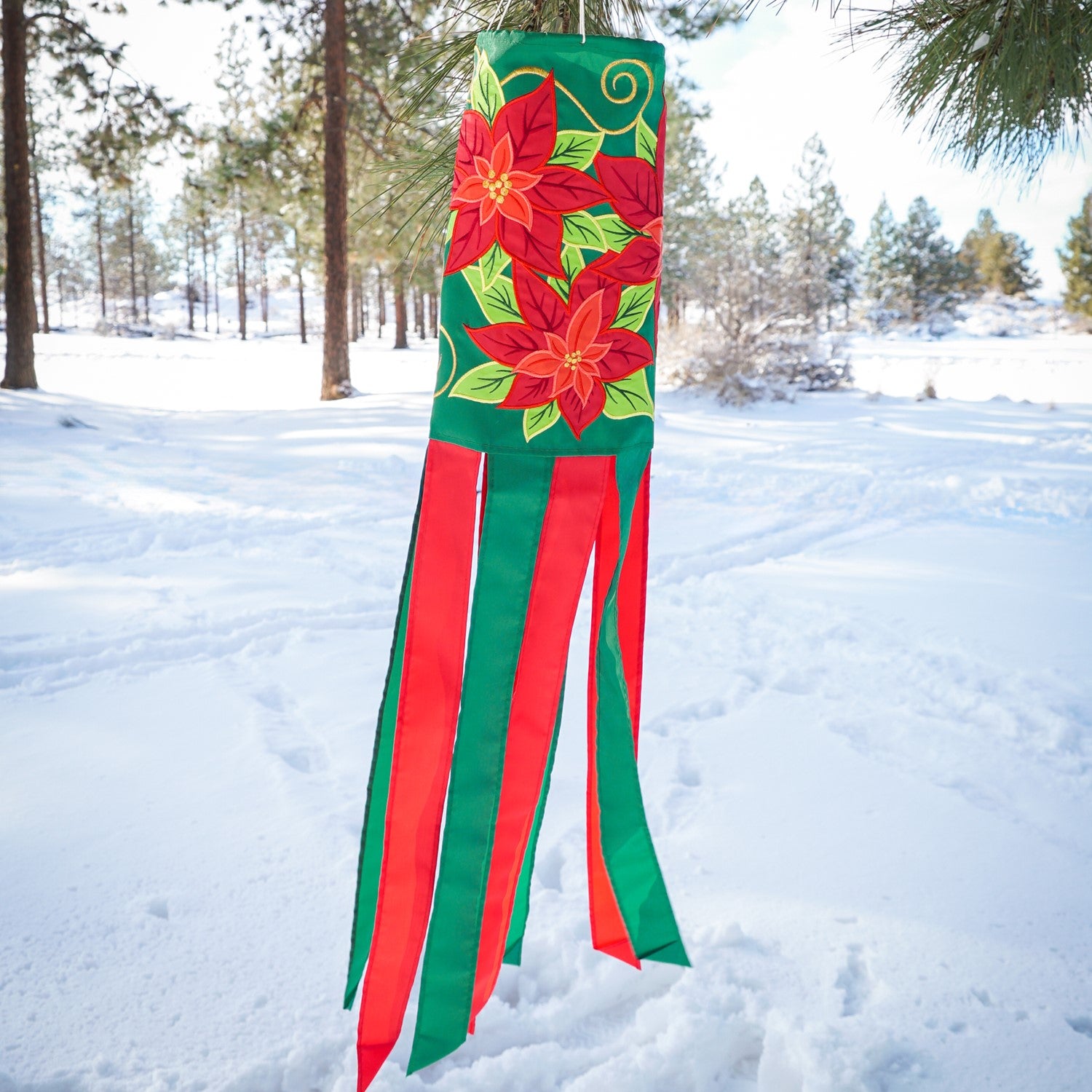 Poinsettia 40" Windsock displaying vibrant red flowers and colorful tails, fluttering in the wind, perfect for winter holiday outdoor decoration.