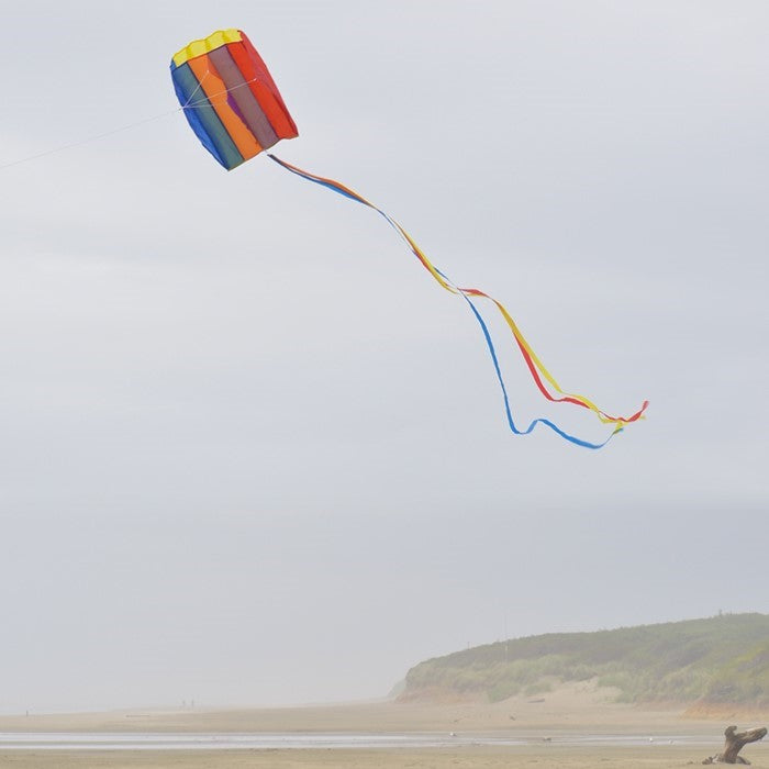 Pouch Parafoil Kite flying majestically in a partly cloudy sky, featuring vibrant rainbow colors and a streamlined design for easy flight.